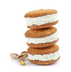 Sweet delicious ice cream cookie sandwiches and pistachios on white background