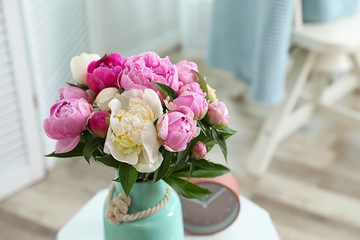 Vase with bouquet of beautiful peonies on table in room. Space for text