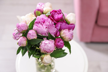 Vase with bouquet of beautiful peonies on table in room, above view. Space for text