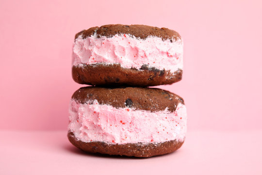 Sweet delicious ice cream cookie sandwiches on color background