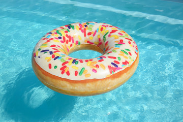 Obraz na płótnie Canvas Bright inflatable doughnut ring floating in swimming pool on sunny day