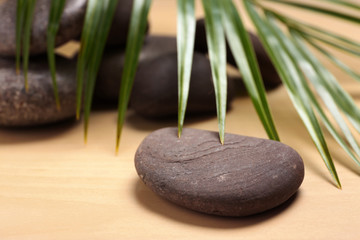 Obraz na płótnie Canvas Spa stones with palm leaf on wooden background