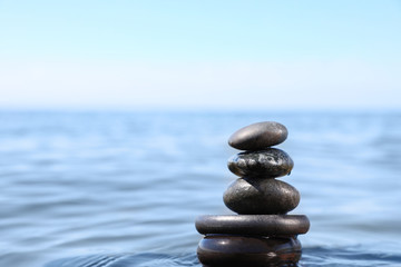 Stack of stones in sea water, space for text. Zen concept