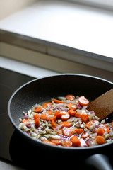 Roasting carrot and onion on olive oil. Selective focus.