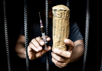 Drugs and prison cell concept. Drug addict man with syringe using drugs.Dark theme,