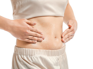 Beautiful young woman applying body scrub against white background