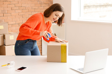 Young woman packing box indoors