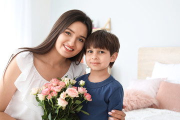 Fototapeta na wymiar Happy mother and son with bouquet of flowers at home