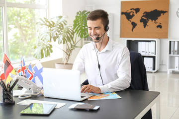 Male travel agent working in office - obrazy, fototapety, plakaty