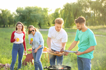 Friends cooking tasty food on barbecue grill outdoors