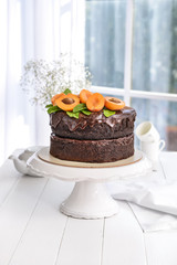 Stand with tasty chocolate cake on white table