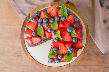 Stand with tasty chocolate cake on wooden table