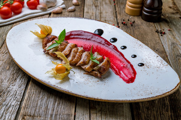 Duck breast with berry sauce on wooden background