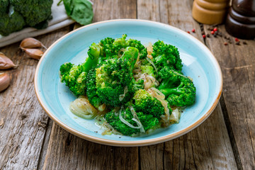 broccoli fried with onions on wooden background
