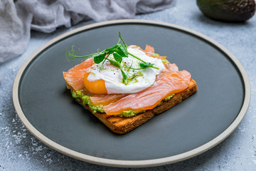 poached egg with salmon and avocado on a white plate