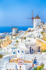 Fototapeta premium Travel Destinations. Picturesque Cityscape of Oia Village in Santorini Island Located on Volcanic Calderra at Daytime. Traditional Windmills on Background.