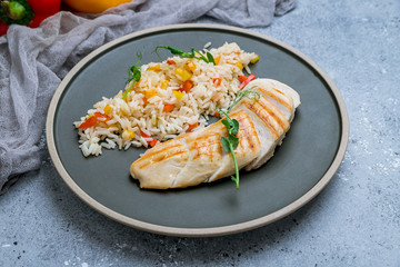 sliced Grilled chicken Breasts with rice and vegetables on grey plate
