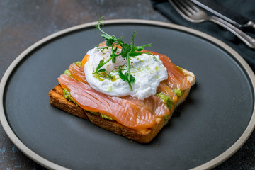 poached egg with salmon and avocado on a white plate
