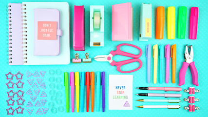 Back to school or workspace colorful stationery on aqua blue background, overhead flat lay.