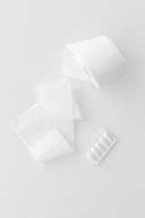 Proctology concept with toilet paper roll and rectal suppository on white background top view