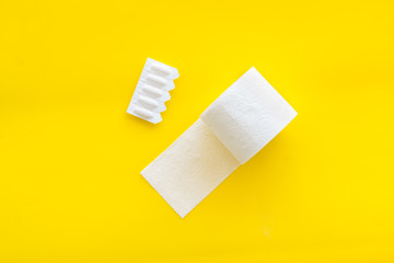 Proctology concept with toilet paper roll and rectal suppository on yellow background top view