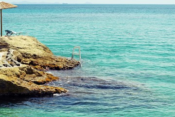 Turquoise beach on a rock that stretches out into the sea, island of Aegina, Greece