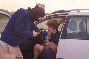 criminal accident, burglar threatening the car driver with a pistol on the parking