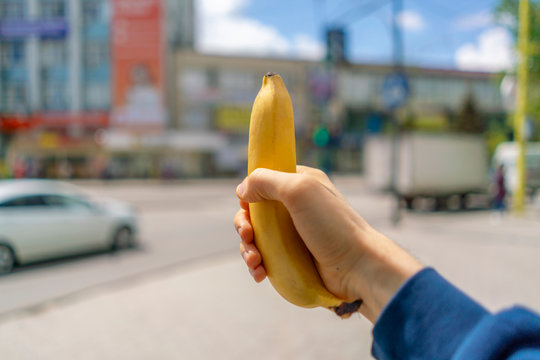 First Person View Of Hand Hold Fresh Ripe Banana, Meal Or Snack In The City Streets