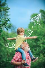 Grandfather talking to grandson. Little boy and grandfather raising hands over sunset sky enjoying...