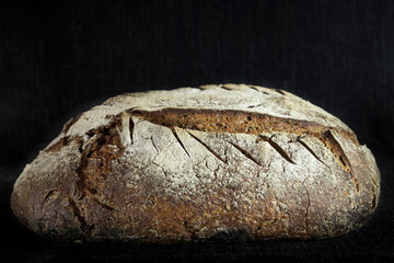 Loaf (or miche) of French sourdough, called as well as Pain de campagne, on display on a black background. Pain de Campagne is a typical French huge loaf of bread abiding by traditional codes