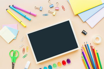 School supplies stationery, colour pencils, paints, paper on pastel orange background, back to school concept with free copy space for text, modern elementary education. Kids desk, flat lay, overhead