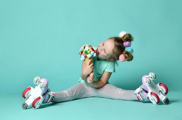 Kid girl in roller skates sits on the floor at free text copy space holds a big and tasty ice-cream in waffles cone