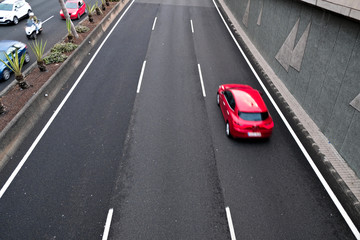 A red car in movement on a black asplalt road, intentional movement / zoom effect.