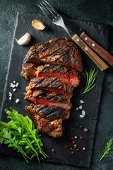 Sliced steak ribeye, grilled with pepper, garlic, salt and thyme served on a slate cutting Board on...