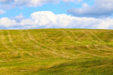 green meadow on the hill against the sky and clouds