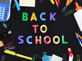 Back to School on black background framed by school supplies