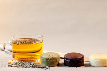 Cheese cakes, a cup of tea and dried tea leaf with spatula on paper. Sweetmeat concept. Macha, choco and original flavor.