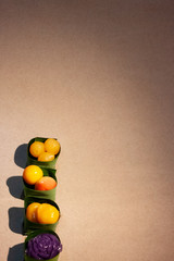 Thai sweets in banana leaves that are arranged in rows. Purple rose steamed layer cake, golden jackfruit seeds, thai mung bean marzipan and golden drops.