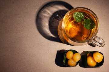 Thai sweets in banana leaves that are arranged with cup of tea on brown paper. Golden jackfruit...