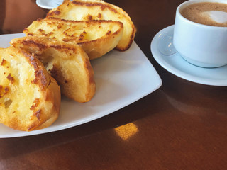 Brazilian breakfast.  Capuccino cup and toasted bread with butter background.