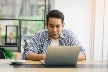 Smart Asian man working with laptop in cafe, work concept