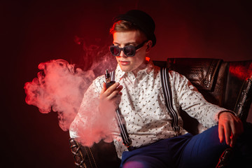 Vaping. Dapper guy with a vape. A man blows smoke sitting in a chair. A person smokes an electronic...