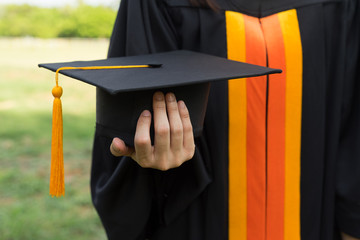 Close up focus of university graduate holds degree certificate and graduation cap celebrates in the  graduation ceremony. University graduate show diploma certificate.