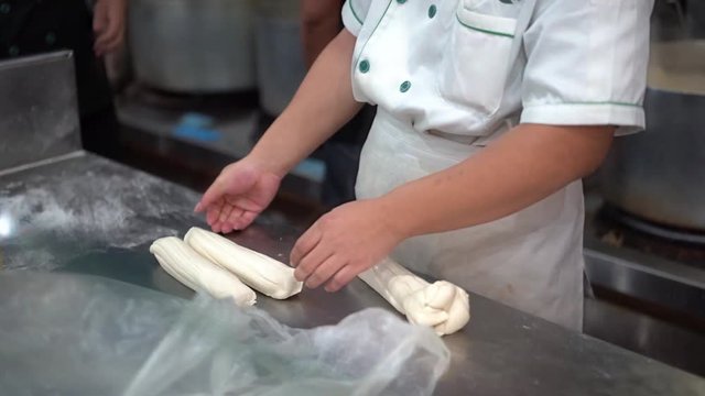 Making dough hand pulled noodles, repeatedly stretch dough to produce long thin strands.
