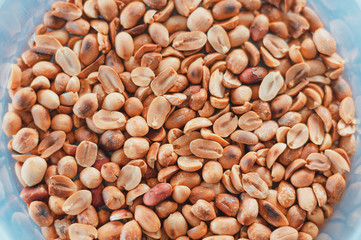 Closeup roasted peanuts in white plastic bucket. Top view wallpaper.