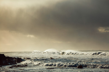 Fototapeta na wymiar Waves and Rocks at Beach at Sunrise