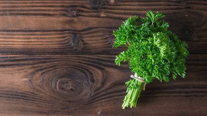 Parsley leaves tied with a rope on a wooden table. Flat lay.