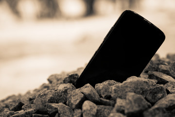 Broken cellphone abandoned and lost among the gravel