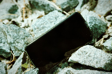 Broken cellphone abandoned and lost among the gravel