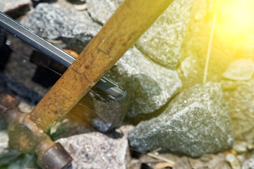 Smartphone broken glass with hammer on gravel stones. Selective focus with sum beam